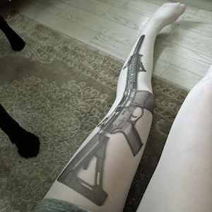 May include: A black and white graphic of a rifle is printed on a white stocking. The image is a detailed illustration of the firearm, showcasing its various components and design.