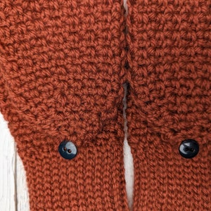 May include: A pair of brown crocheted mittens with black buttons.