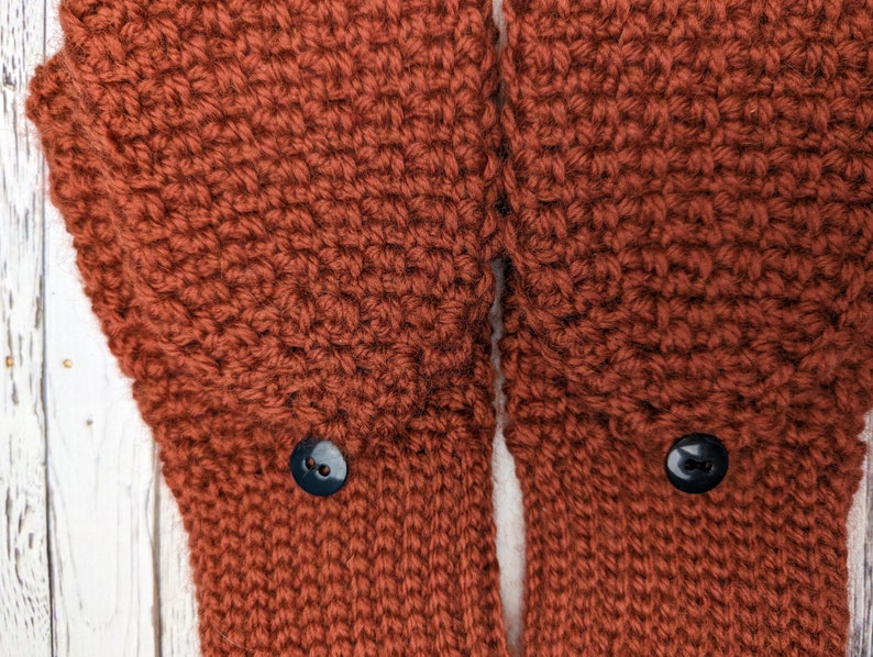 May include: A pair of brown crocheted mittens with black buttons.