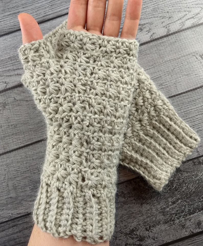 Op de afbeelding: Een paar beige gebreide vingerloze handschoenen met een textuurpatroon. De handschoenen zijn gemaakt van zacht garen en hebben een comfortabele pasvorm.