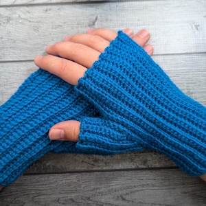 May include: A pair of bright blue fingerless gloves, crafted with a ribbed crochet stitch. The gloves are designed to cover the hand and wrist, leaving the fingers exposed. The texture of the crochet is clearly visible.