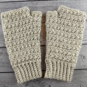 Op de afbeelding: Een paar beige gebreide vingerloze handschoenen met een sterrensteekpatroon.