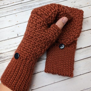 May include: A pair of brown crocheted fingerless gloves with black buttons. The gloves are made with a textured stitch and have a fold-over cuff.