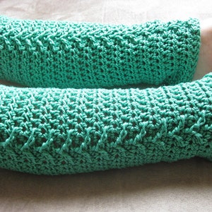 May include: A pair of teal blue crocheted leg warmers. The leg warmers are made with a textured stitch pattern.