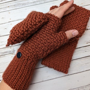 May include: A pair of brown crocheted fingerless gloves with a button on the wrist. The gloves are made with a textured stitch and have a fold-over cuff.