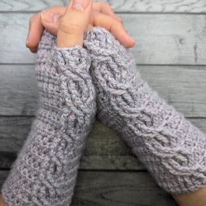 May include: A pair of gray fingerless gloves with a cable knit pattern.