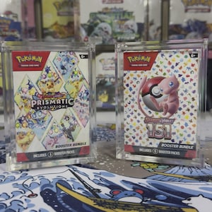 May include: Two Pokemon Trading Card Game booster bundles in clear cases. One features "Prismatic Evolutions" with colorful characters. The other displays "Scarlet & Violet 151" with a pink Mew and a Poke Ball. Both include 6 booster packs.