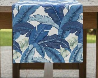 Camino de mesa Tommy Bahama para interiores y exteriores, diseño de palmeras ondulantes, color azul, con hojas de plátano grandes.