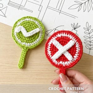 Può includere: Due cartelli circolari all'uncinetto con manici. Uno è verde lime con un segno di spunta bianco, l'altro è rosso con una X bianca. Entrambi hanno un bordo bianco. Il testo CROCHET PATTERN Digital PDF CREATED BY @EMBRILLY è visibile in basso.