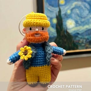 Può includere: Bambola all'uncinetto fatta a mano raffigurante Vincent van Gogh, con cappello giallo, barba arancione, giacca blu e pantaloni gialli. La bambola tiene un girasole giallo. Il testo "CROCHET PATTERN" e "Digital PDF" sono visibili.