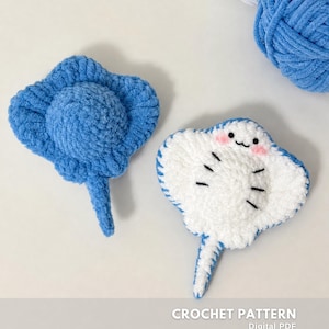 Può includere: Due razze crochet, una blu tinta unita e l'altra bianca con bordi blu, dettagli neri e guance rosa. Il testo "CROCHET PATTERN" e "Digital PDF" sono visibili. Sullo sfondo ci sono gomitoli di lana blu e bianca.