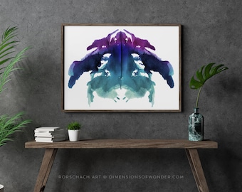 Op de afbeelding: Een ingelijste print van een symmetrisch abstract aquarelontwerp in tinten blauw, paars en groen. Het ontwerp lijkt op een Rorschach-inktveltest. De tekst "Rorschach Art © DIMENSIONSOFWONDER.COM" is onder de afbeelding gedrukt.