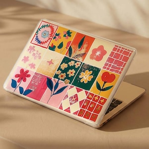 Puede incluir: Una funda para portátil con una cuadrícula de paneles rectangulares coloridos con varios patrones florales y geométricos en tonos rojos, amarillos, verdes y rosas. El diseño incluye flores estilizadas, hojas y motivos de rejilla en una carcasa.