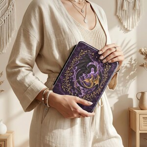 May include: A rectangular tablet case featuring a dark purple, cloudy background with a central illustration of a black and gold dragon curled in a circle. The dragon is framed by an intricate gold vine border with small leaves and stars.