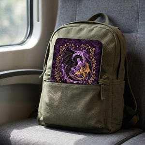 May include: An olive green backpack with a rectangular notebook tucked into the front pocket. The notebook cover features a black dragon and a gold dragon intertwined against a purple lightning background, framed by a gold floral vine pattern.