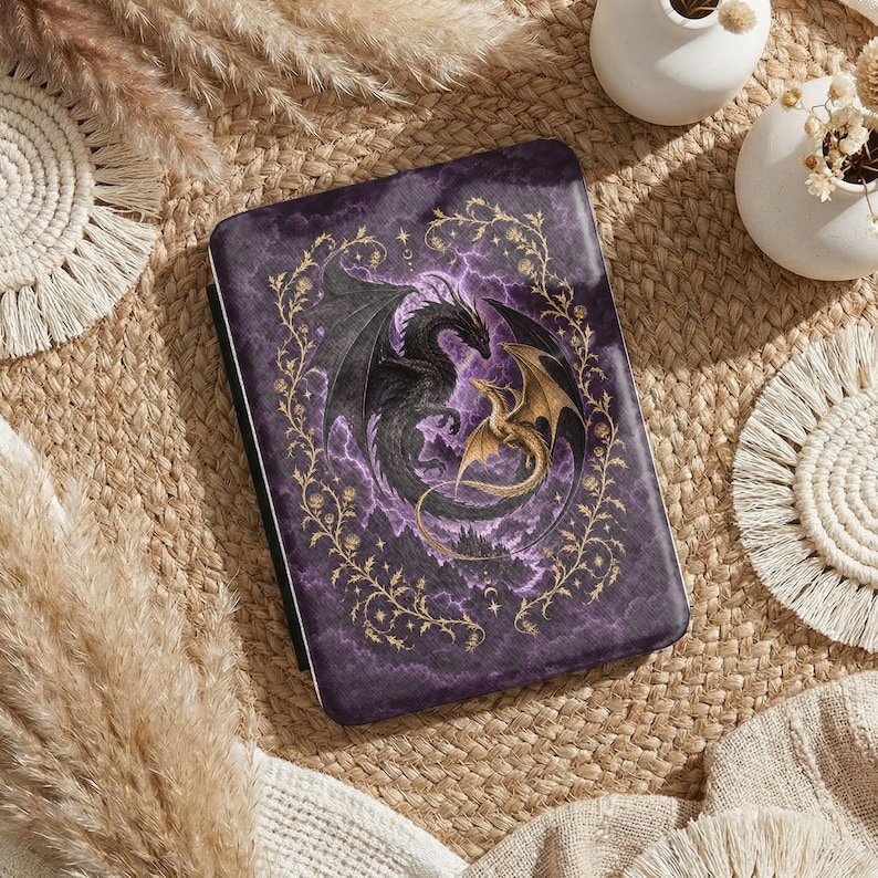 May include: A rectangular e-reader case featuring a dark purple marble background with a central illustration of a large black dragon and a smaller gold dragon intertwined. The design is framed by a delicate gold vine pattern with small stars.