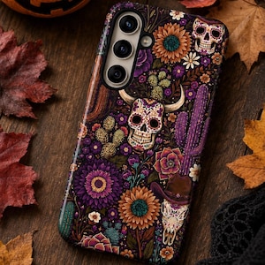 May include: A smartphone case featuring a dark purple background with a vibrant pattern of sugar skulls, sunflowers, cacti, and succulents. The design includes a central skull with horns and a smaller skull wearing a brown cowboy hat.