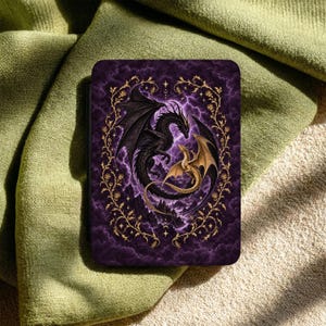 May include: A rectangular tablet case featuring a dark purple, cloudy sky background with a large black dragon and a smaller gold dragon intertwined in a circular formation, all framed by an intricate gold vine and floral border design.