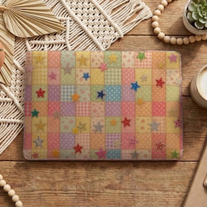 May include: A rectangular laptop hard shell case featuring a patchwork grid pattern of pastel-colored squares in shades of pink, yellow, blue, and lavender. The surface is decorated with a repeating print of small, multi-colored glittery stars.