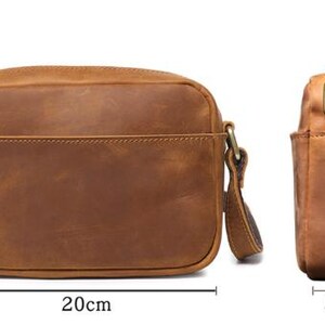 Puede incluir: Bolso bandolera de cuero marr&oacute;n, de forma rectangular, con un bolsillo frontal. El bolso mide 20 cm de largo, 15 cm de alto y 5 cm de ancho. Tiene una correa para el hombro y herrajes met&aacute;licos.