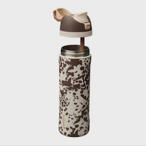 May include: A stainless steel water bottle with a brown and cream cow print design. The lid is open, revealing the interior. The lid is brown and cream with a flip-top opening. The bottle is cylindrical and has a silver rim.