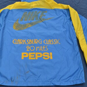 May include: A blue and yellow windbreaker jacket with the Nike logo and the text "Clarksburg Classic 20 Miles Pepsi" on the back.