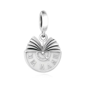 May include: A silver charm featuring a circular clock face with Roman numerals and a central hand, topped with an open book design. The piece includes a polished bail at the top for attachment, showcasing a metallic finish and detailed engraving.