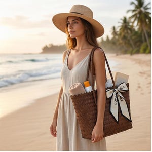 May include: A woman wearing a beige sun hat and dress, carrying a woven brown tote bag. The bag contains a rolled towel, sunscreen, and a book. The beach scene includes the ocean and palm trees.