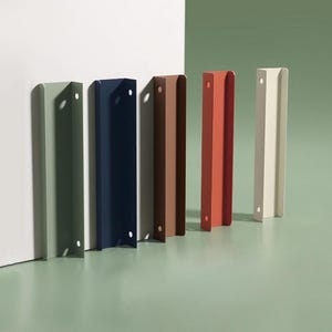 Puede incluir: Seis tiradores de metal para armarios en varios colores, incluyendo verde salvia, azul marino, marrón y crema. Cada tirador tiene forma rectangular con un asa curvada y un agujero de montaje.