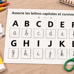 May include: A worksheet with the text "Associe les lettres capitales et cursives" displays uppercase and lowercase letters A through L. Colored pencils, a glue stick, scissors, and a notepad are on the wooden surface.