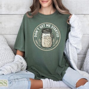 Green t-shirt with "Don't get me started" text and a jar graphic.