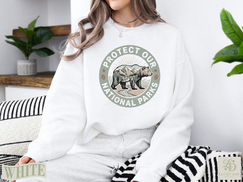 White sweatshirt with "Protect Our National Parks" circular graphic featuring a bear.