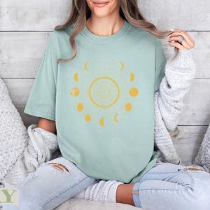 Light mint green t-shirt with a yellow moon phase and zodiac design.