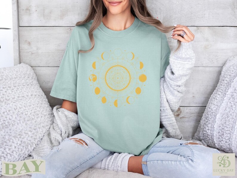 Light mint green t-shirt with a yellow moon phase and zodiac design.