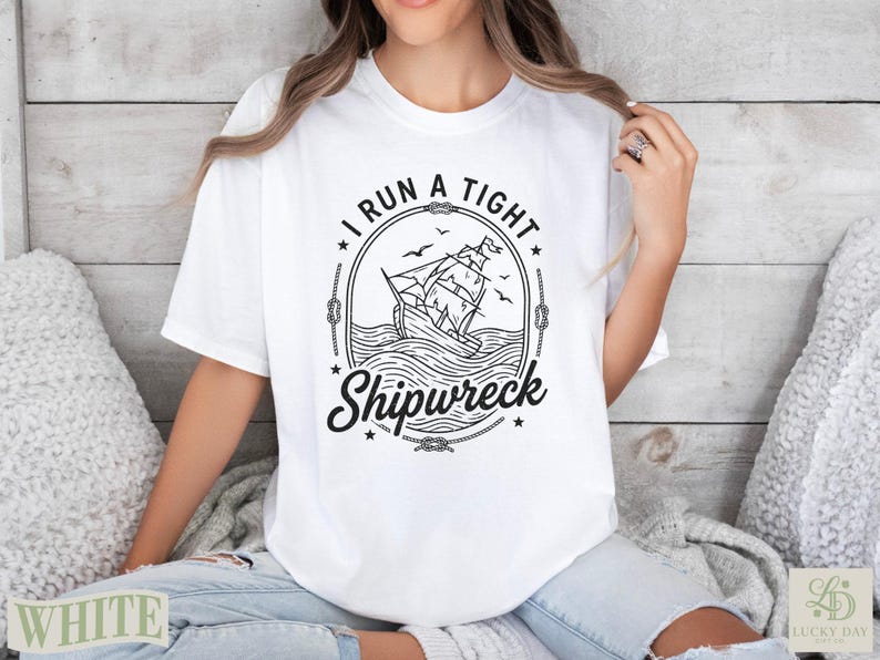 White t-shirt with a graphic featuring a sailing ship and the text "I run a tight shipwreck."