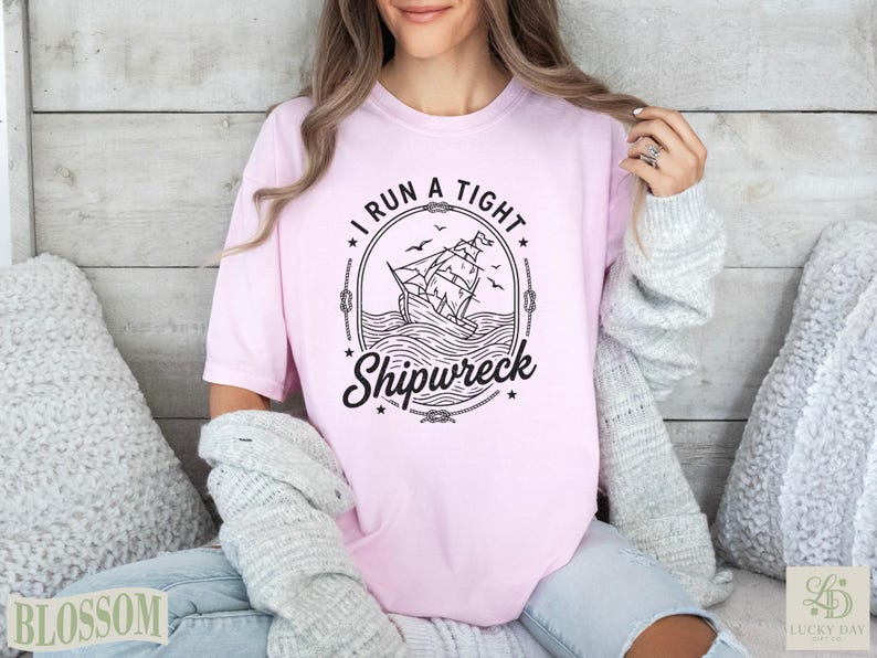 Pink t-shirt with "I RUN A TIGHT SHIPWRECK" text and a sailing ship graphic.