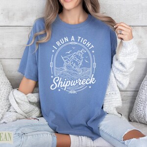 Blue t-shirt with "I Run a Tight Shipwreck" text and sailing ship graphic.