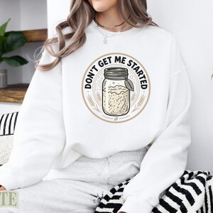 White sweatshirt with a round graphic of a jar and text that says "Don't Get Me Started".