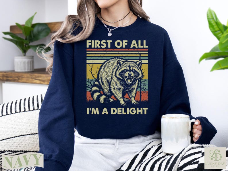 Navy sweatshirt with vintage raccoon graphic and text "FIRST OF ALL I'M A DELIGHT".
