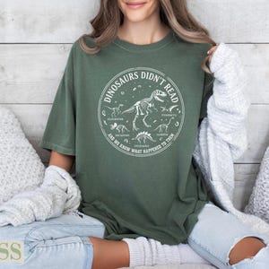 Green t-shirt with circle graphic of dinosaurs and text about them.
