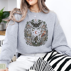 Grey crewneck sweatshirt with forest animal and moth graphic design.