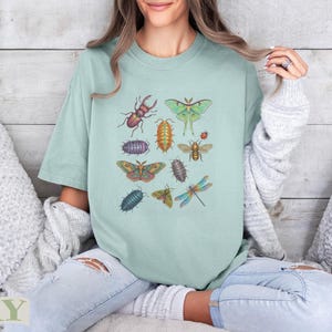 T-shirt with colorful botanical illustrations of various insects, including beetles, moths, and dragonflies.