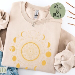 Sand colored sweatshirt with celestial moon phase mandala design.