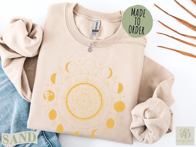 Sand colored sweatshirt with celestial moon phase mandala design.