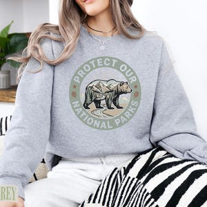 Grey sweatshirt with "Protect Our National Parks" graphic featuring a bear and mountains.
