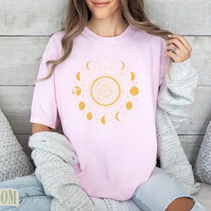 Pink t-shirt with a gold moon phase mandala design.