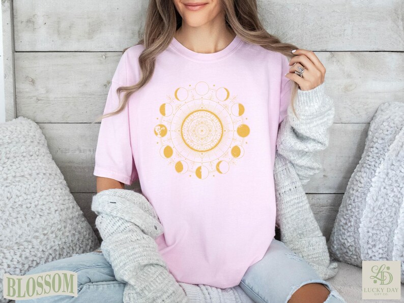 Pink t-shirt with a gold moon phase mandala design.
