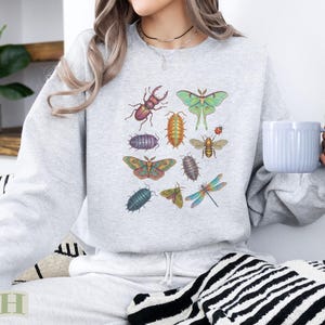 Light gray sweatshirt with colorful illustrations of various insects, including a beetle, moth, bee, and dragonfly.