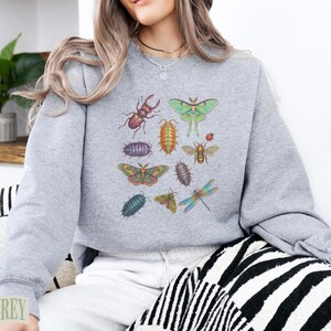 Grey sweatshirt with colorful insect illustrations, including beetles and moths.