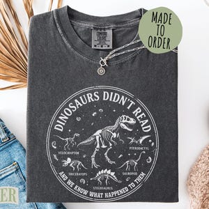 Black t-shirt with "Dinosaurs Didn't Read" text and dinosaur skeletons.